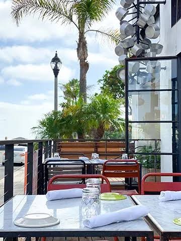 The Atrium at 264 Fresco — hanging pans, palms, and set tables