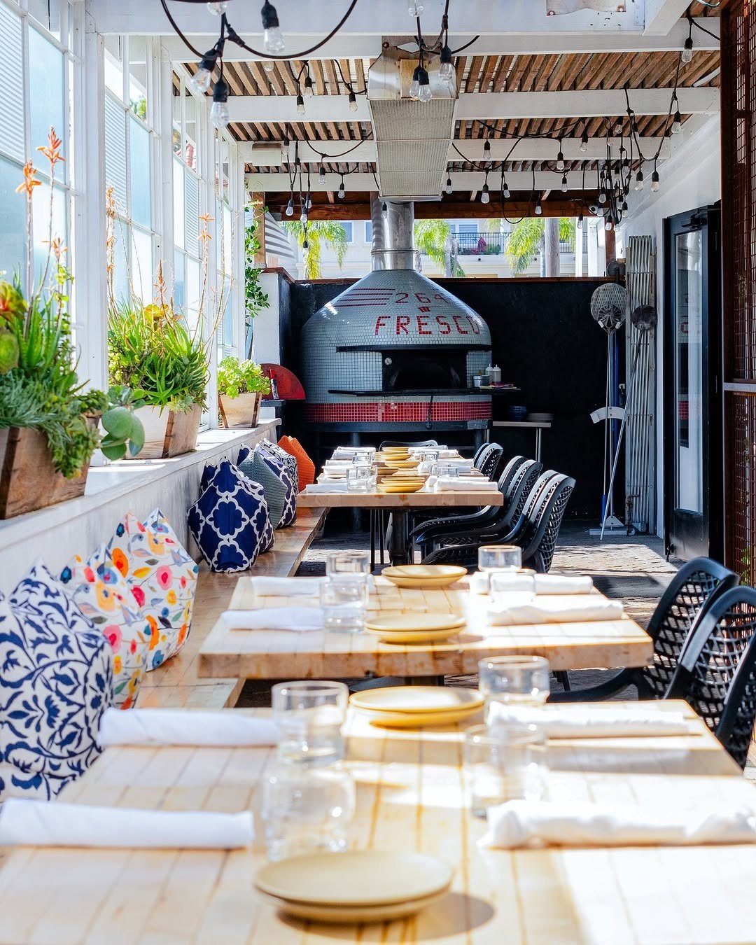Wood-fired pizza and wine on the 264 Fresco patio, oven burning behind