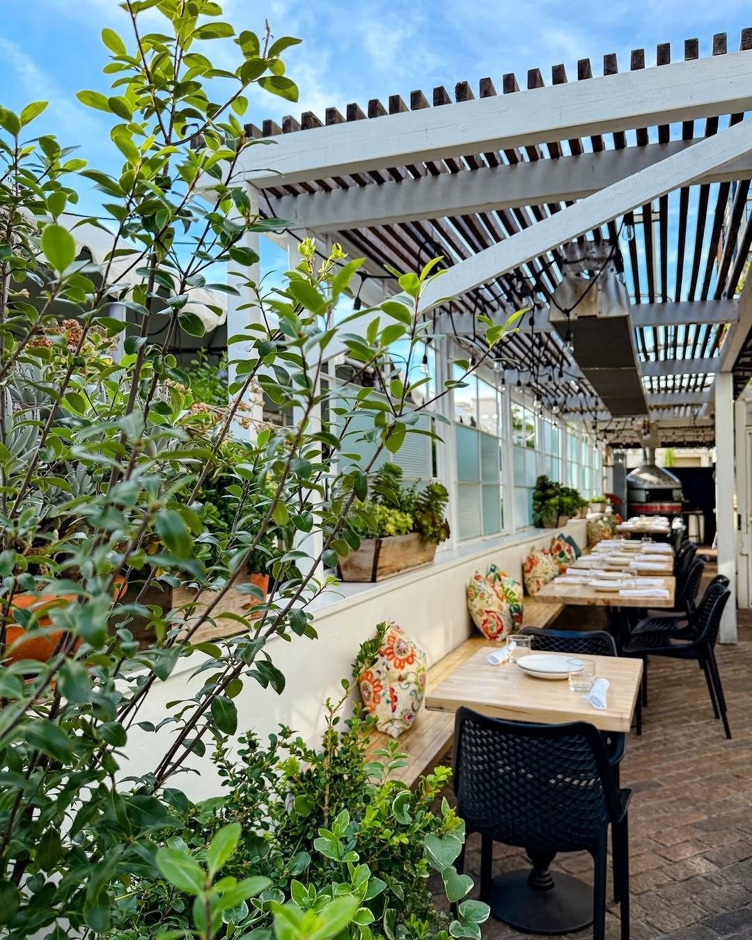 The Pizza Patio at 264 Fresco — umbrellas, greenery, and tables in the village