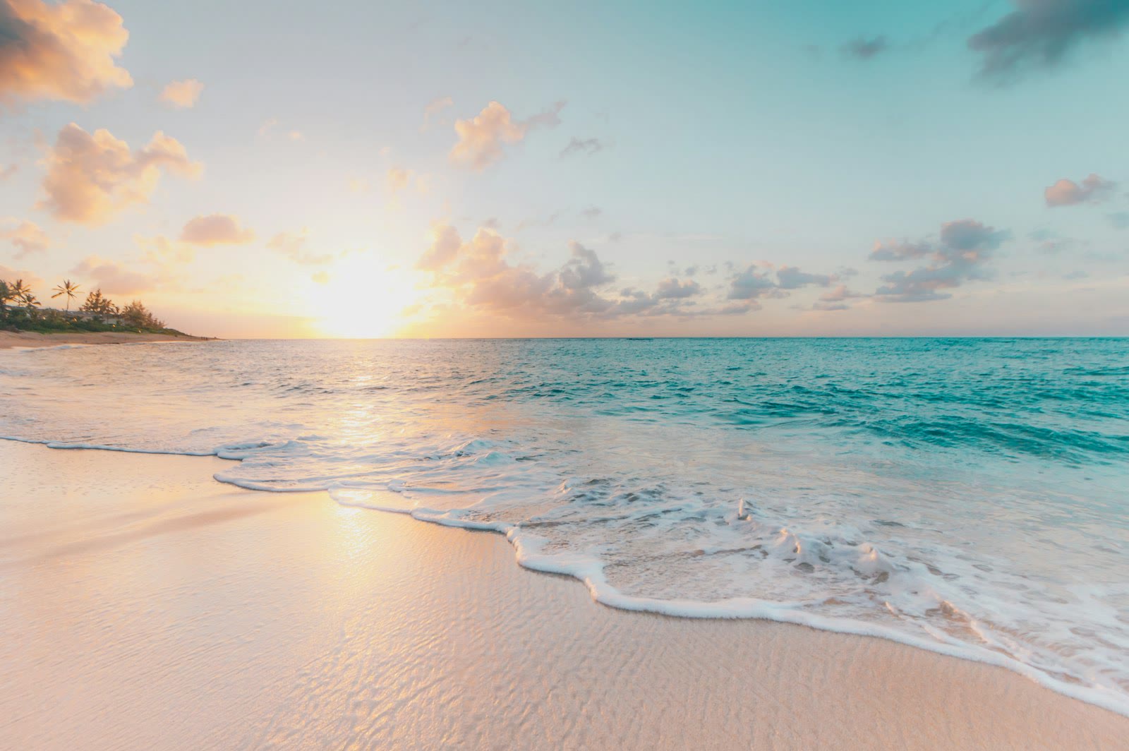 Golden morning light over a calm shoreline with soft turquoise waves